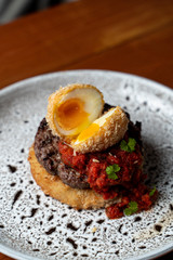 Close up of marbled beef steak with deep fried egg, chili sauce and potato hash brown