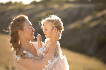 Portrait of a beautiful young mom holds her beloved daughter in her arms. Parental love, little...