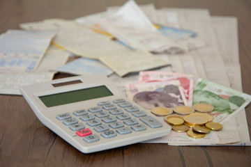 Stack of bills, money and calculator on wooden table