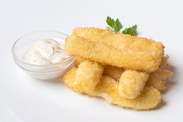 Cheese sticks breaded, with sauce and herbs, on a platter. Close-up.