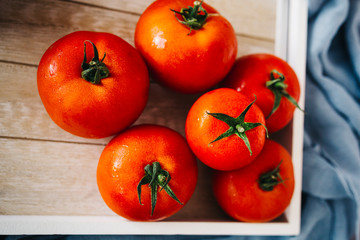 Fresh, pink and red tomatoes on white, different backgrounds and in a wooden crate