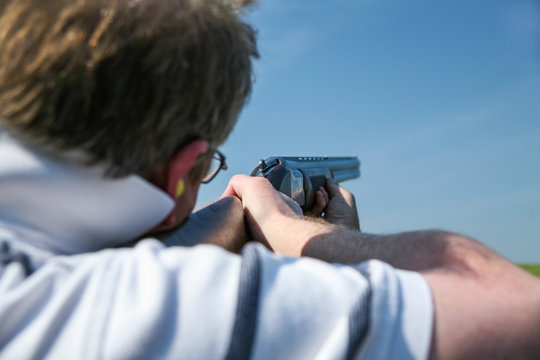 A man readies himself as he holds his rifle in anticipation of a clay pigeon