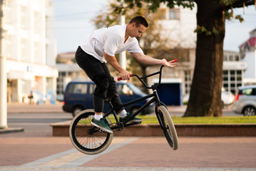 A young guy on a BMX bike, wraps the steering wheel in a jump.