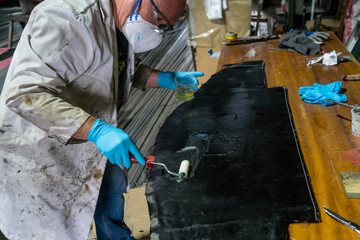 Man with protections on hands, eyes and mask, repairing a piece of carbon and epoxy resin.