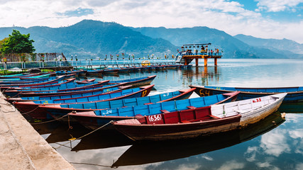 Colourful boats at shore of beautiful Phewa lake. Pokhara, Nepal with Annapurna range in background. 