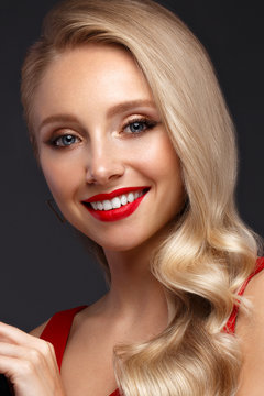 Beautiful blonde in a Hollywood manner with curls, natural makeup and red lips. Beauty face and hair.