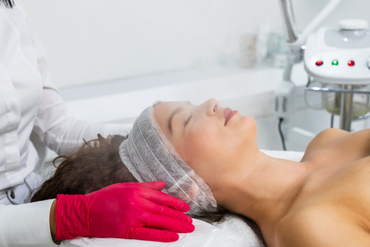 Beautiful woman relaxing during a facial steam treatment at a beauty spa.