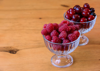 red raspberries and cherries in bulk in glass bowls