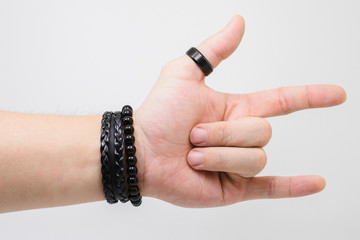 Rock hand, hand of a white man wearing a thick black ring on the thumb and some black wrist...