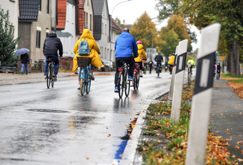 Gruppe von Fahrradfahrern mit Regenkleidung fÃ¤hrt im Regen auf einer StraÃŸe â€“ selektiver Fokus - obrazy, fototapety, plakaty