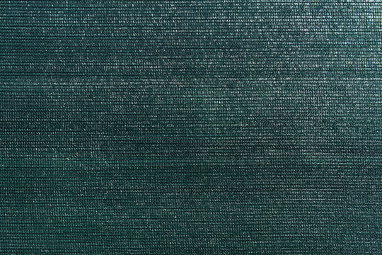 Dark green knitted polyethylene mesh background. Agro sun shade net textured surface sample. Greenhouse equipment. Artificial material backdrop.