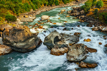 River flows trough rocky valley in Himalaya mountains in Nepal during sunny summer day.	
