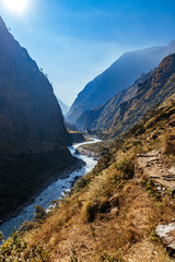 Fototapeta na wymiar River flows trough rocky valley in Himalaya mountains in Nepal during sunny summer day. 