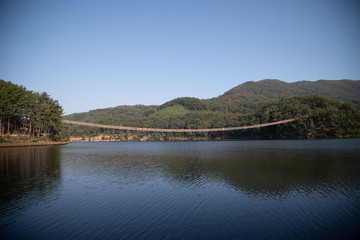 Fototapeta na wymiar Suspension bridge connected to the mountain across the lake