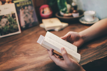 Relaxing moments, Young man opening and reading a book in coffee shop. Relax time on holiday concept travel, Thailand. Color of vintage Tone cozy feeling.