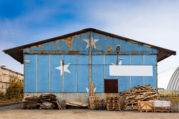 Close-up of the national flag of Federal States of Micronesia painted on the metal wall of a large warehouse the closed territory on a summer day. The concept of storage of goods