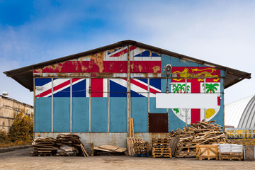 Close-up of the national flag of Fiji. painted on the metal wall of a large warehouse the closed territory on a summer day. The concept of storage of goods, entry to a closed area, tourism