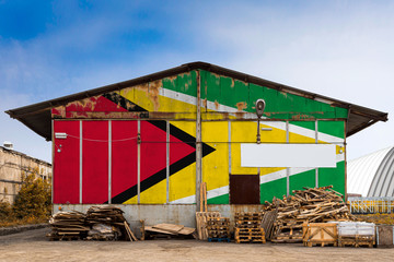 Close-up of the national flag of Guyana. painted on the metal wall of a large warehouse the closed territory on a summer day. The concept of storage of goods, entry to a closed area, tourism