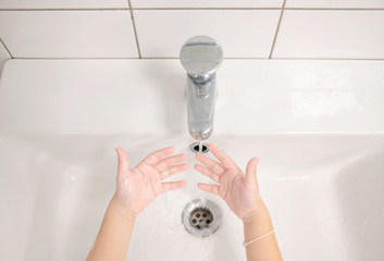 Little boy is washing his hands himself in the bathroom. Care for children concept. Background. Copy space.