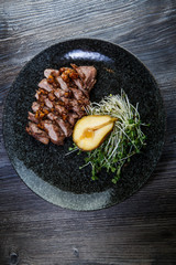 top view of baked beef meat slices with half of grilled pear