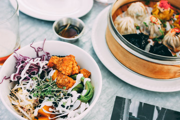 Pan-Asian food - vegetable salad bowl and different dim sums in restaurant. Lunch for two with beer