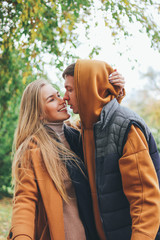 Fototapeta premium Happy young couple in love teenagers friends dressed in casual style kissing on city street in cold season