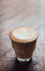Close up coffee cup with latte art on grunge wood table at cafe