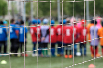 net soccer goal in focus in the background out of focus young football players in red