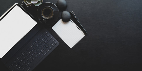 Dark trendy workplace with tablet and office supplies