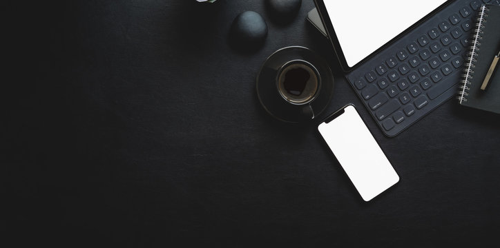 Dark modern workplace with tablet and office supplies on black leather background