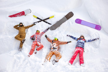 Happy friends having fun lying on snow aerial view. Ski and snowboard concept