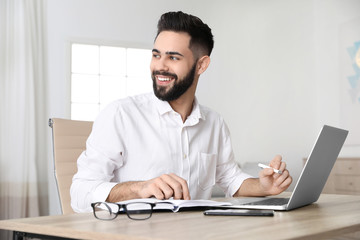 Handsome young man working at table in home office