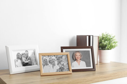 Framed photos on cabinet near white wall