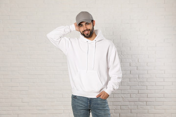 Portrait of young man in sweater at brick wall. Mock up for design