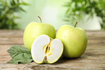 Fresh ripe green apples on wooden table against blurred background