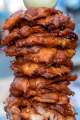 Large pieces of meat on a spit at street food market in Thailand. Crilled skewered chiken meat on spit. Fast food.