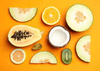 Flat lay composition with tasty melon and fresh tropical fruits on orange background