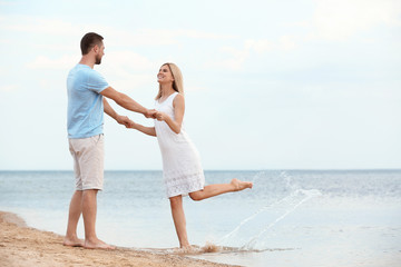 Fototapeta na wymiar Happy romantic couple dancing on beach, space for text
