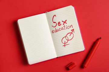 Notebook with phrase "SEX EDUCATION" on red background, flat lay. Space for text