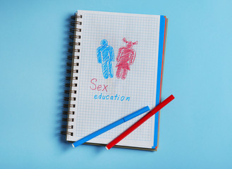 Notebook with phrase "SEX EDUCATION" on blue background, top view