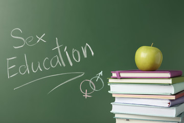 Books and apple near chalkboard with phrase 