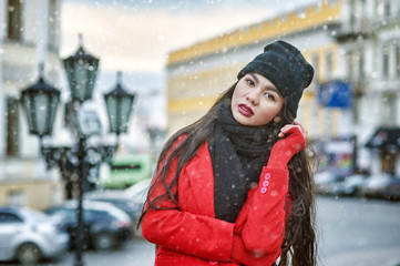 Young woman on a winter day in the city .  Girl in a hat and a red warm coat