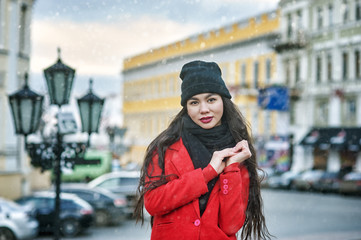 Young woman on a winter day in the city .  Girl in a hat and a red warm coat