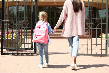 Young mother taking her little child to school outdoors