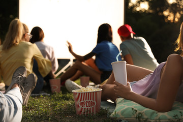 Young people with popcorn and drink watching movie in open air cinema, closeup