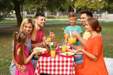 Happy families with children having picnic at table in park