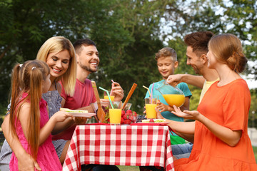 Happy families with children having picnic at table in park