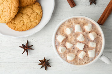 Fototapeta na wymiar Composition with delicious hot cocoa drink and cookies on white wooden background, flat lay