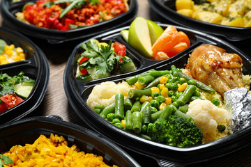 Lunchboxes with different meals on table, closeup. Healthy food delivery