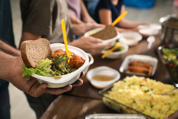 Poor man holding plate with food in charity centre, closeup